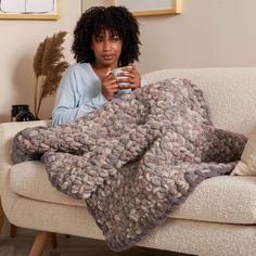 a woman sitting on a couch holding a cup