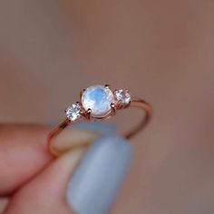 a close up of a person's hand holding a ring with an oval stone