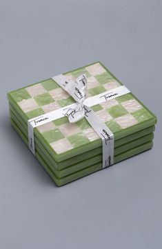 a stack of green and white checkered coasters with ribbon tied around the edges