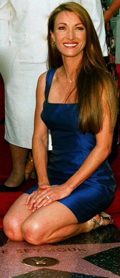 a woman in a blue dress sitting on the hollywood walk of fame with her legs crossed