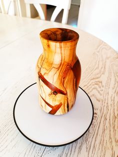 a wooden vase sitting on top of a white plate