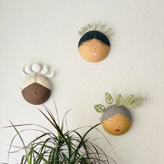 three decorative wall hangings on the wall above a potted plant