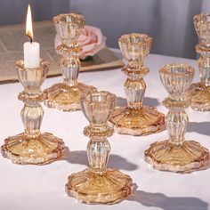 a group of glass candlesticks sitting on top of a table next to a candle