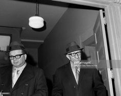 two men in suits and hats are standing together