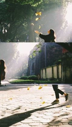 two people are playing with leaves in the sun on a cobblestone street, and one person is throwing them into the air