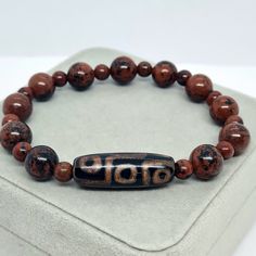 Agate Tibetan Dzi bead bracelet with Red Obsidian stone beads. Lucky amulet for a gift. Bracelet size made to order. Please send me the size of your wrist so the bracelet will fit perfectly. Bead size: Dzi - 3×1 cm/1.16×0.42 inches. Bronzite - 6 and 11 mm/0.24 and 0.4 inches. If you choose to pack No.2, leave me a message about which stamp you would like (Crown, Cloverleaf, Just Smile). I will choose the color of the stamp at my discretion if you do not have any other wishes 🙂 You may also want Red Agate Beaded Bracelets For Meditation, Red Agate Beaded Bracelet For Meditation, Spiritual Brown Beaded Bracelets With Oval Beads, Spiritual Brown Beaded Bracelet With Oval Beads, Obsidian Beaded Bracelets As Gift, Amulet Bracelet With Round Beads For Gift, Amulet Style Bracelet With Round Beads As Gift, Hand-strung Obsidian Beaded Bracelets As Gift, Spiritual Beaded Bracelets With Natural Stones For Good Luck