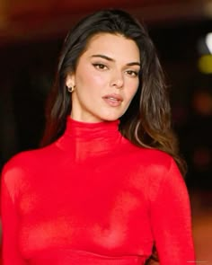 a woman in a red dress posing for the camera with her hand on her hip