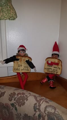 two elfs sitting on top of a couch with bread in the shape of letters