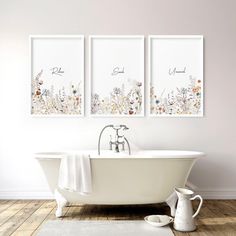 three framed pictures hang above a bathtub in a bathroom with wood floors and white walls