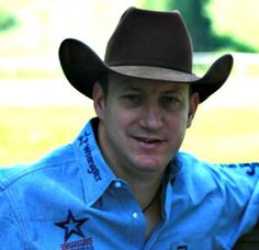 a man in a cowboy hat sitting on a bench with his hand on his hip