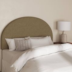 a bed with white sheets and pillows in a bedroom