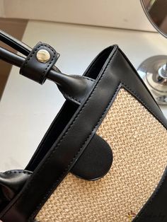 a close up of a purse on a table with a wine glass in the background