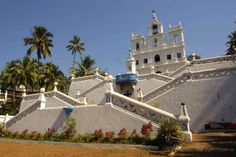 an ornate white building with blue balconies on the roof and stairs leading up to it