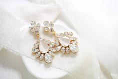 Handcrafted with care, our gold Ivory cream crystal Bridal statement earrings are a perfect choice for your special day ! - Handmade to order with Premium European crystals - Soldered by hand in our studio and stones are handset by me- Ivory cream center accent stone and clear stones- 18K gold plated brass- Earrings measure 2.75" x 1.25"- Each piece is gift wrapped PLEASE ALLOW APPROX 10 BUSINESS DAYS FOR COMPLETION BEFORE SHIPPING This is an original design by © Treasures by Agnes Bridal Statement Earrings, Clear Stone, Brass Earrings, White Opal, Bridal Earrings, Bridal Hair, Statement Earrings, Stone Color, Your Special