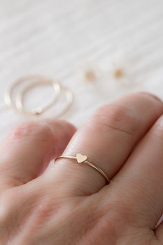 "This adorable and dainty heart ring is the perfect gift for you or someone special. With its matte, satin finish of solid 14k yellow gold, this petite heart creates a warm and romantic look, perfect for everyday wear or special occasions. A great way to celebrate a friendship, honor your bridesmaids, or say \"I love you\" to family. The perfect gift for mom, stack one for each of her loves! ❤️ ✥ Solid 14k yellow gold ✥ Ethically sourced ✥ Beautifully boxed ✥ Gift wrap available at checkout ✥ Ha Dainty Stackable Midi Rings For Valentine's Day, Valentine's Day Gift Stackable Rings, Dainty Stackable Heart Ring Gift, Dainty Stackable Gift Rings With Heart Charm, Dainty Heart-shaped Stackable Rings For Anniversary, Minimalist Stackable Rings With Heart Charm For Anniversary, Dainty Heart Charm Stackable Gift Rings, Dainty Heart-shaped Stackable Anniversary Rings, Dainty Stackable Heart Ring For Valentine's Day