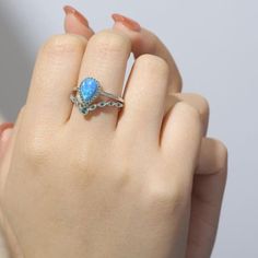 Indulge in the timeless beauty of our Lab-Grown 9 x 6 mm Teardrop Blue Opal Cabochon Ring, a treasure designed to evoke emotions and create lasting memories. Surrounded with vibrant Nano Emerald accent stones of varied sizes, this stunning teardrop shape holds deep symbolism, representing emotions and new beginnings.    Crafted with enduring 925 sterling silver, this ring showcases rhodium plating, enhancing its brilliance and protecting it from tarnish. The total weight of the ring is 4 grams, Teardrop Birthstone Jewelry For Promise Ring, Sapphire Teardrop Jewelry With Gemstone Accents, Fine Jewelry Teardrop Crystal Ring As Gift, Blue Teardrop Birthstone Rings, Sapphire Teardrop Gemstone Rings, Teardrop Sapphire Birthstone Jewelry, Teardrop Opal Jewelry For Anniversary, Blue Teardrop Promise Ring, Teardrop Jewelry With Accent Stones For Gift