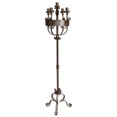 an iron candle holder with five candles on it's stand, and four smaller candles in the middle