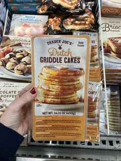 a person holding up a sign in front of some desserts and other items at a store