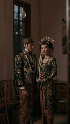 a man and woman dressed up in traditional thai garb standing next to each other