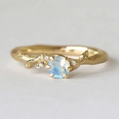 a yellow gold ring with an oval blue topazte and diamond accents