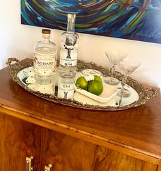 a tray that has some bottles and glasses on it with two limes in front of it