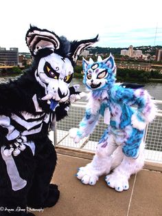 two people in costumes standing next to each other on a bridge over looking the water