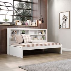 a white bed with a book shelf on top of it next to a wooden floor