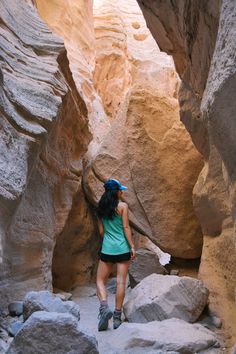 a woman walking through a narrow slot in the desert