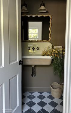 an open door leading to a bathroom with a sink and mirror on the wall above it