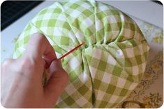 someone is sewing on the green and white checkerboard fabric with a red needle