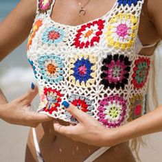 a woman wearing a colorful crochet top on the beach