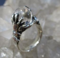 "This is a Hand Cast Sterling Silver Ring with a unique \"Crystal Ball\" design. It is set with a 10 mm Natural Quartz Crystal Ball. This original design has two hands holding the crystal ball. Unique ring, surely will be noticed everywhere you go. The ring is about 7/16 inch wide on top and tapers to a plain shank in the back. It is 7/16 inch tall. Truly Magical ! This ring is made in a size 7 1/4. I will wrap the ring in a gift box and mail in a small box within 1-2 days of purchase, usually o Unique Silver Jewelry With Round Cut, Unique Clear Rings, Unique Clear Round Rings, Unique Round Cut Silver Jewelry, Mystical Sterling Silver Crystal Ring, Spiritual Sterling Silver Crystal Ring For Formal Events, Spiritual Sterling Silver Crystal Ring For Formal Occasions, Hallmarked Sterling Silver Crystal Ring, Sterling Silver Crystal Ring Fine Jewelry