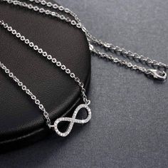 Centered between the two lengths of shiny silver tone chain, this miniature eternity symbol appears to float along the neck. Completely encrusted in micro CZ stones creating incredible shimmer. At only 2 cm this is truly subtle and graceful. This necklace is perfect for women, teens or young children. Length: 18 inch chain Stones: CZ Metal: Sterling Silver, 3 layers of platinum plating. Comes in a gift box. (Reg $45.99) Silver Charm Necklace With Delicate Cubic Zirconia Chain, Silver Cubic Zirconia Charm Necklace With Delicate Chain, Silver Diamond Charm Necklace With Delicate Chain, Silver Infinity Clavicle Chain Jewelry, Silver Infinity Clavicle Chain Necklace, Silver Infinity Jewelry, Silver Infinity Necklace With Delicate Chain, Dainty Silver Diamond Chain Necklace, Silver Infinity Metal Necklace