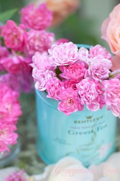 pink flowers are in a blue vase on a table