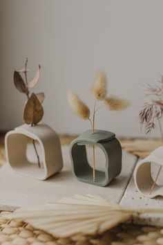 three small vases sitting on top of a table next to dried flowers and leaves