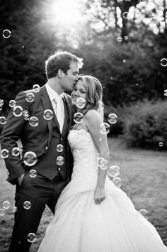 a bride and groom standing in front of bubbles