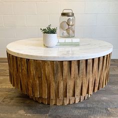 a white marble top coffee table with wooden slats on the bottom and a plant in front