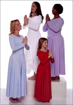 four women in different colored dresses are standing on a pedestal and applauding each other