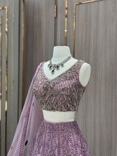 Our stunning Net Fabric Party Wear Lehenga in striking purple is perfect for making a bold statement at any special occasion, featuring intricate embroidery work in gold and silver threads. Purple Sharara With Cutdana And Traditional Drape, Elegant Purple Choli With Traditional Drape, Purple Sharara For Reception With Traditional Drape, Purple Traditional Drape Sharara For Reception, Purple Cutdana Lehenga For Reception, Designer Purple Art Silk Sharara, Traditional Drape Lavender Choli For Wedding, Lavender Choli With Dupatta In Traditional Drape, Purple Art Silk Anarkali Set For Reception