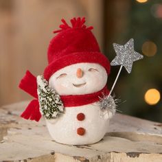 a small snowman with a red hat and scarf holding a star on top of it