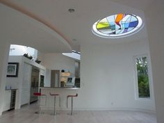 an empty room with white walls and wood flooring has a circular stained glass window on the ceiling