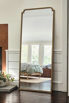 a mirror sitting on top of a wooden floor next to a fire place in a living room