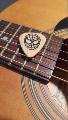 a wooden guitar with a spider - man emblem on it's fret picker