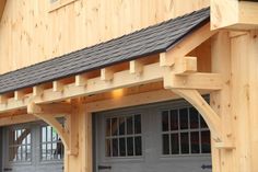 a wooden building with two garage doors and a porch attached to the side of it