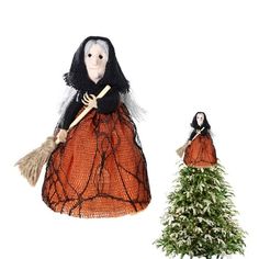 the doll is dressed in an orange dress and holding a broom next to a small christmas tree