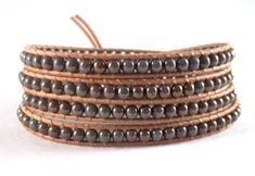 Leather wraps are a great way to add a fun, boho, chic look to any outfit.  They can be worn alone or with a bangle or another wrap for an interesting cluttered look.  The 4 mm bluish, lavender with  bronze glaze Czech glass beads, are nestled between natural Greek leather cording.  A delightful, textured, copper button finishes the look.  The bracelet is threaded twice for additional strength and durability.  It measures 32- 1/2" for a loose, comfortable fit for most size 7 - 7 1/2" wrists. This bracelet will arrive ready for gifting. I ship USPS first class.  I include delivery confirmation, when available, at no extra cost to you.  I will supply you with a tracking number.  For additional information on shipping, please see my shop policy page. I welcome all questions!  Thank you for yo Adjustable Brown Beaded Wrap Bracelet, Brown Hippie Wrap Bracelet For Festivals, Hippie Brown Wrap Bracelet For Festivals, Festival Hand Wrapped Wrap Bracelet, Beaded Brown Wrap Bracelet For The Beach, Beaded Brown Wrap Bracelet For Beach, Brown Beaded Wrap Bracelet For Beach, Adjustable Wrap Bracelet With Black Round Beads, Adjustable Wrap Bracelet With Black Beads