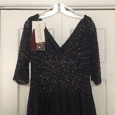 a black dress with sequins hanging on a hanger in front of a door