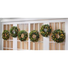 christmas wreaths are hung on the wall in front of windows