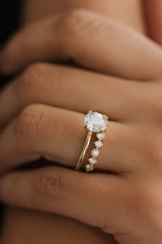 a woman's hand with a diamond ring on top of her finger and an engagement band