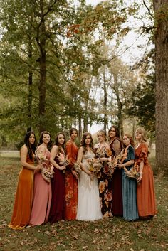 a group of women standing next to each other in front of some trees and leaves